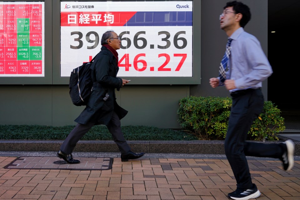 People walk in front of an electronic stock board showing Japan's Nikkei index at a securities firm Tuesday, Feb. 4, 2025, in Tokyo. (AP Photo/Eugene Hoshiko)