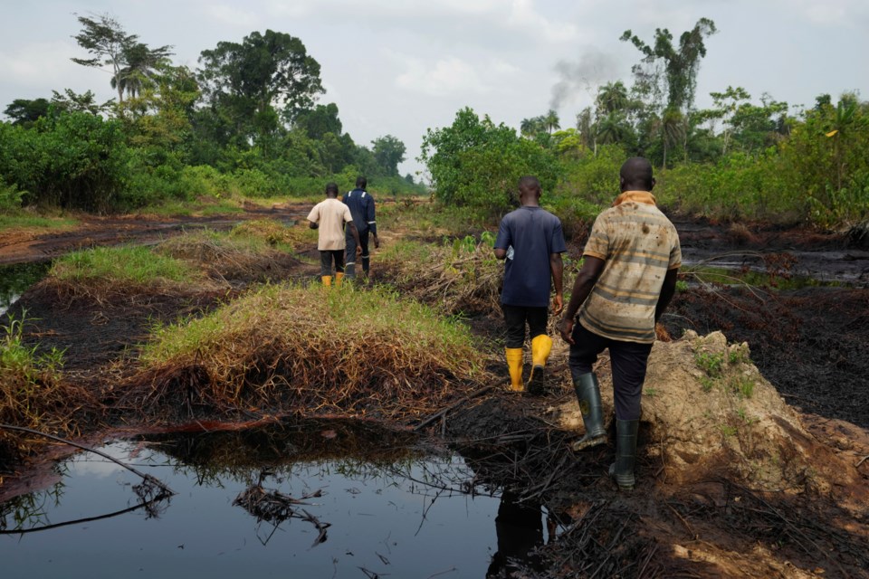 FILE - People walk amid an oil spill in the Niger Delta in village of Ogboinbiri, Nigeria, Dec. 11, 2024. (AP Photo/Sunday Alamba, File)