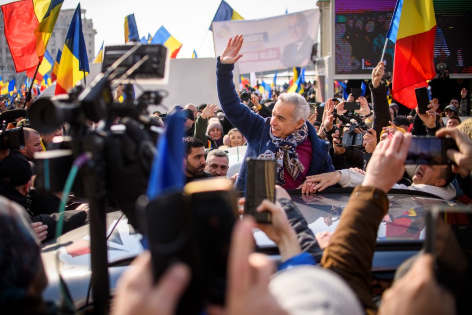 FILE - Calin Georgescu, the winner of Romania's first round of presidential election, annulled by the Constitutional Court, waves to supporters gathered for a protest outside the Romanian parliament in Bucharest, Romania, Saturday, Feb. 22, 2025. (AP Photo/Alexandru Dobre, File)