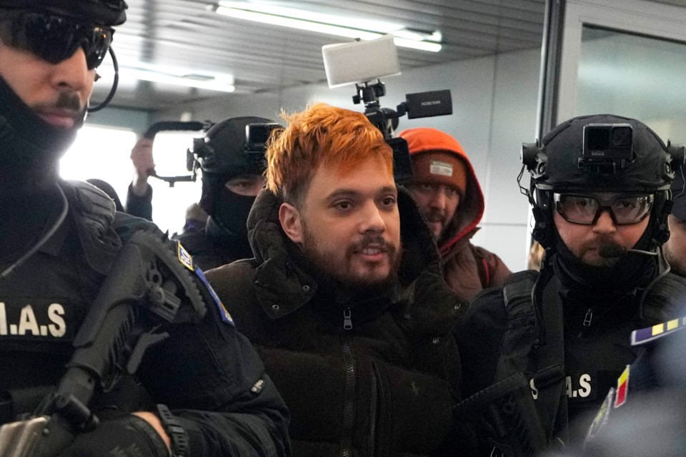 Mohamed Amra, nicknamed ''The Fly", is escorted by armed police officers at the Henri Coanda international airport in Otopeni, Romania, Tuesday, Feb. 25, 2025, before being extradited to France. (AP Photo/Vadim Ghirda)