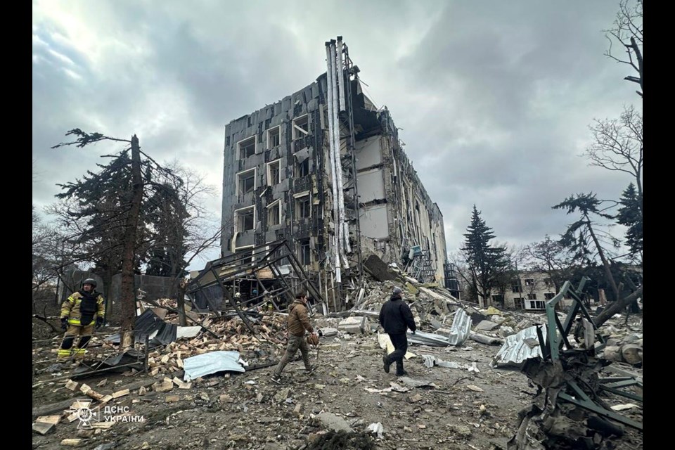 In this photo provided by the Ukrainian Emergency Services on Tuesday, Feb. 4, 2025, rescue workers walk in front of a building that was heavily damaged by a Russian strike in Izium, Ukraine. (Ukrainian Emergency Service via AP)