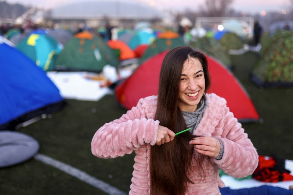 A student brushes her hair after waking up on a soccer stadium during a protest over the collapse of a concrete canopy that killed 15 people more than two months ago, in Indjija, Serbia, Friday, Jan. 31, 2025. (AP Photo/Armin Durgut)