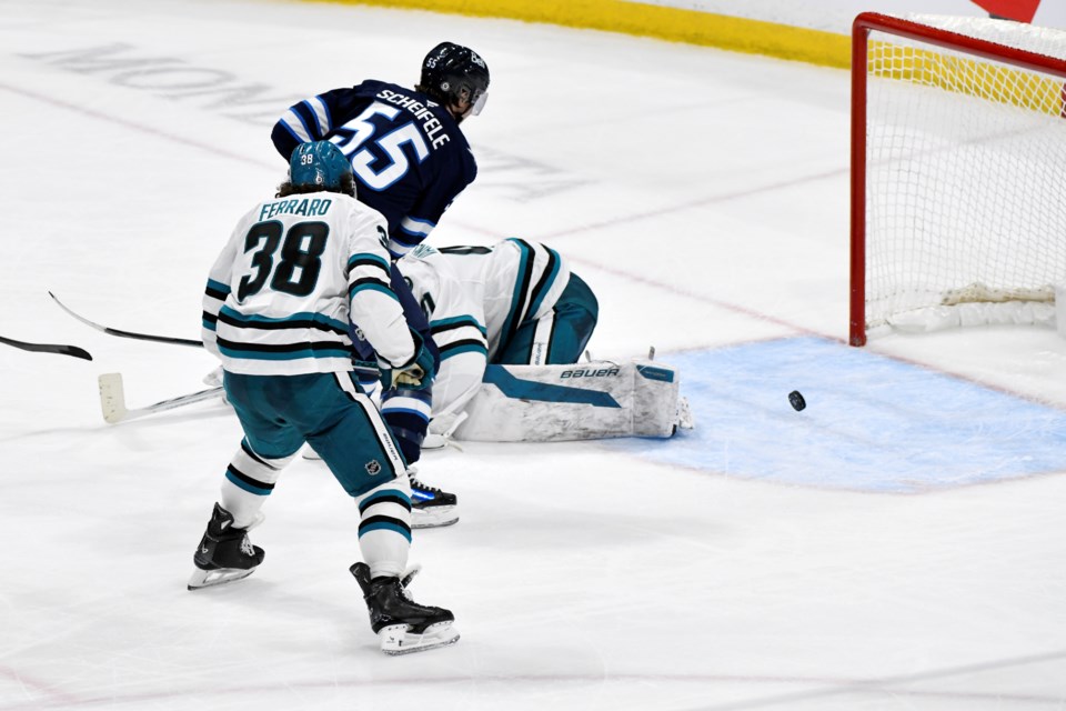 Winnipeg Jets' Mark Scheifele (55) scores his game-winning goal in overtime on San Jose Sharks goaltender Vitek Vanecek (41) during an NHL hockey game in Winnipeg, Manitoba, Monday, Feb. 24, 2025. (Fred Greenslade/The Canadian Press via AP)