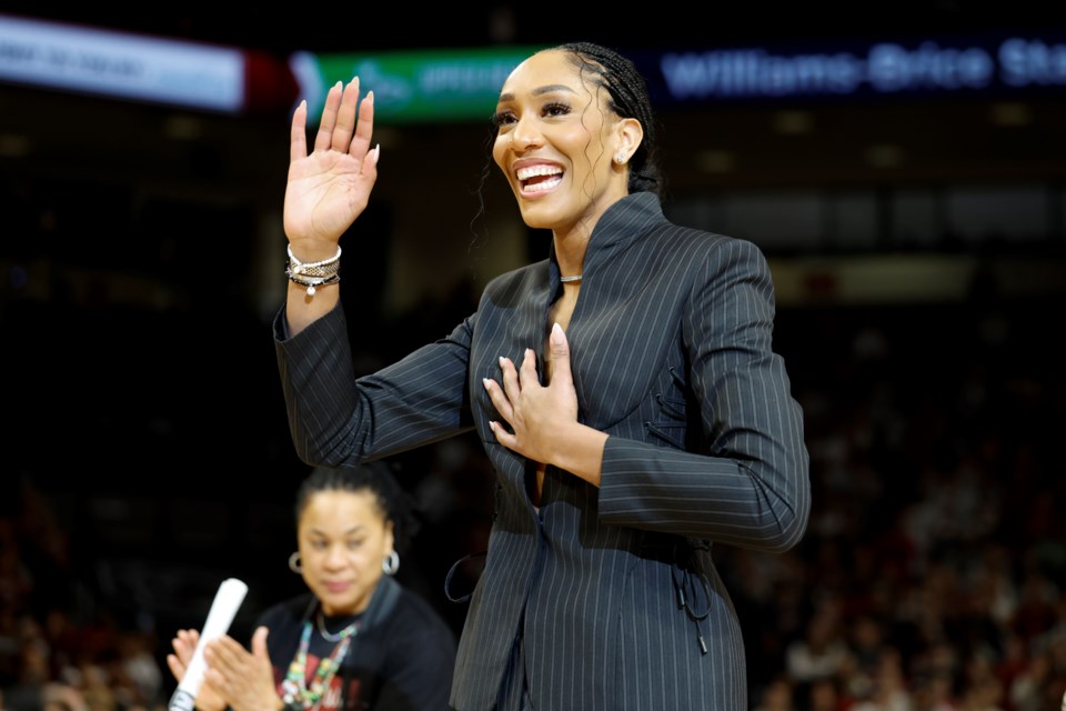 A'ja Wilson, center, stands with her parents Eva and Roscoe Wilson as they watch her number be retired during a ceremony before an NCAA college basketball game between South Carolina and Auburn in Columbia, S.C., Sunday, Feb. 2, 2025. (AP Photo/Nell Redmond)