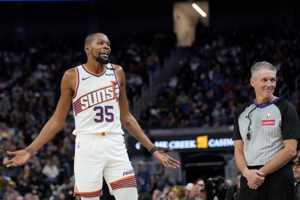 Phoenix Suns forward Kevin Durant (35) gestures toward former NBA player Gary Payton, sitting with fans, as referee Scott Foster, right, reacts during the second half of an NBA basketball game between the Golden State Warriors and the Suns in San Francisco, Friday, Jan. 31, 2025. (AP Photo/Jeff Chiu)