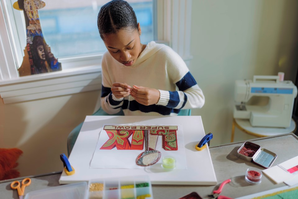 In this undated photo provided by the NFL, New Orleans artist Tahj 'Queen Tahj' Williams works on the Super Bowl logo. (NFL Via AP)