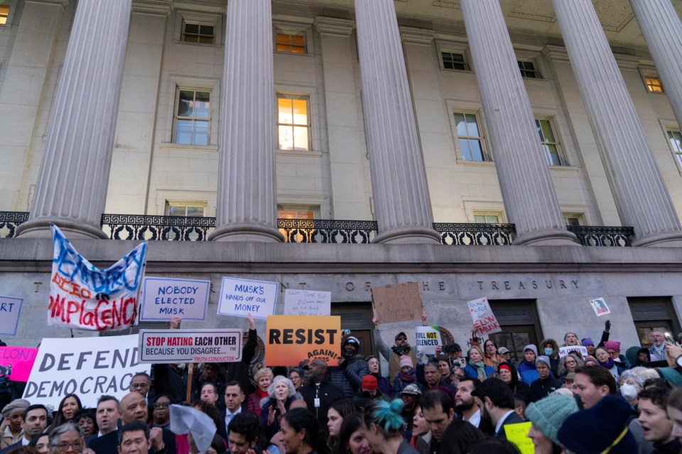 People listen to speakers during a rally against Elon Musk outside the Treasury Department in Washington, Tuesday, Feb. 4, 2025. (AP Photo/Jose Luis Magana)