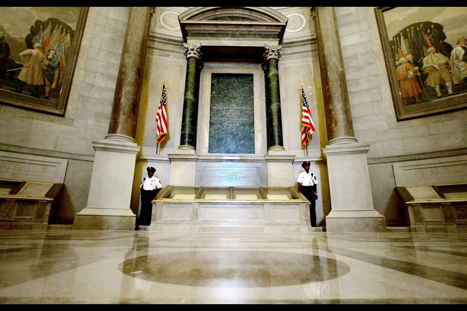 FILE - Guards stand next to the U.S. Constitution in the newly renovated Rotunda of the National Archives in Washington, Sept. 16, 2003, during a media tour. (AP Photo/Ron Edmonds)