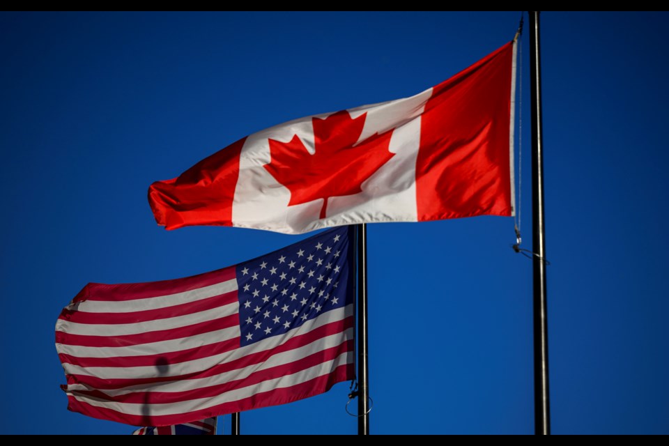 The flags of Canada and the United States fly outside a hotel in downtown Ottawa, on Saturday, Feb. 1, 2025. (Justin Tang/The Canadian Press via AP)