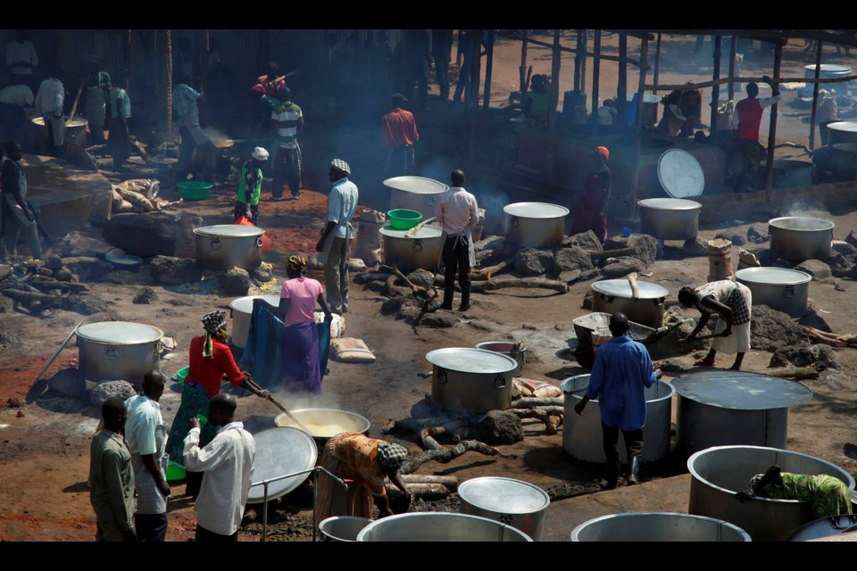 FILE - Refugees prepare food including maize porridge donated by USAID and known locally as posho, during the visit of U.N. in Adjumani, Uganda, Aug. 29, 2016. (AP Photo/Stephen Wandera, File)