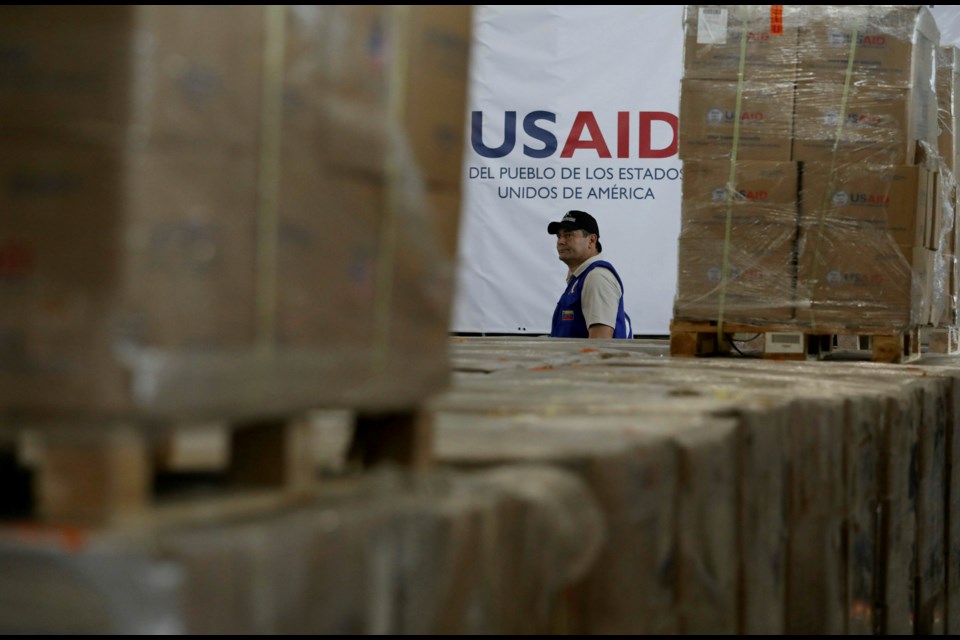 FILE - A man walks past boxes of USAID humanitarian aid at a warehouse at the Tienditas International Bridge on the outskirts of Cucuta, Colombia, Feb. 21, 2019, on the border with Venezuela. (AP Photo/Fernando Vergara, File)