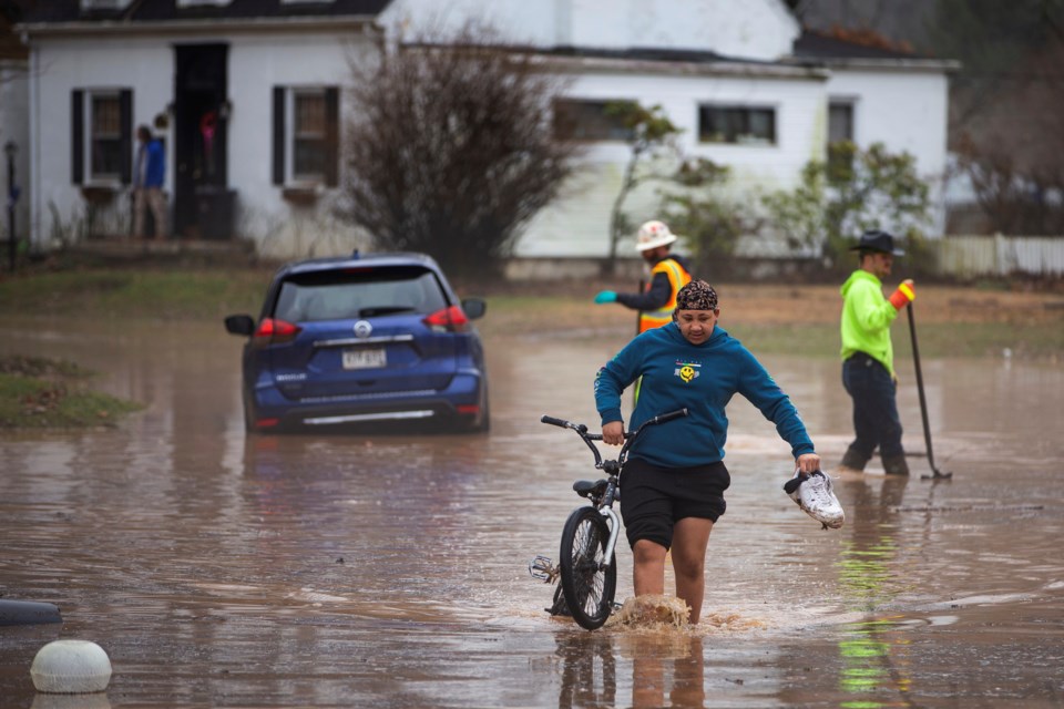 Siquoia Jackson, of Huntington, pulls a bike through the floodwater while trying to travel through the Enslow Park neighborhood on Thursday, Feb. 6, 2025, in Huntington, W.Va. (Ryan Fischer/The Herald-Dispatch via AP)