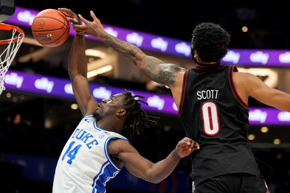 Duke guard Sion James (14) and Louisville forward James Scott reach for a rebound during the first half of an NCAA college basketball game in the championship of the Atlantic Coast Conference tournament, Saturday, March 15, 2025, in Charlotte, N.C. (AP Photo/Chris Carlson)