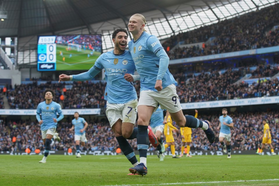 Manchester City's Erling Haaland, right, celebrates with his teammate Omar Marmoush after scoring his side's opening goal during the English Premier League soccer match between Manchester City and Brighton and Hove Albion at Etihad stadium in Manchester, England, Saturday, March 15, 2025. (AP Photo/Ian Hodgson)