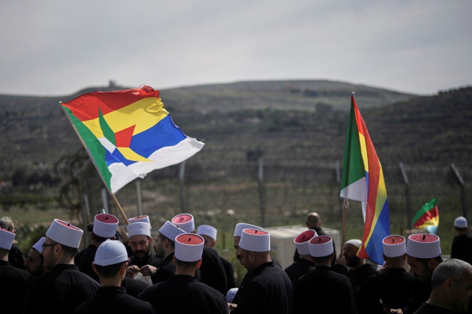 Druze clerics stand near the border, as they wait for buses carrying members of the Syrian Druze community to cross from Syria in the village of Majdal Shams, in the Israeli-controlled Golan Heights, Friday, March 14, 2025. (AP Photo/Leo Correa)