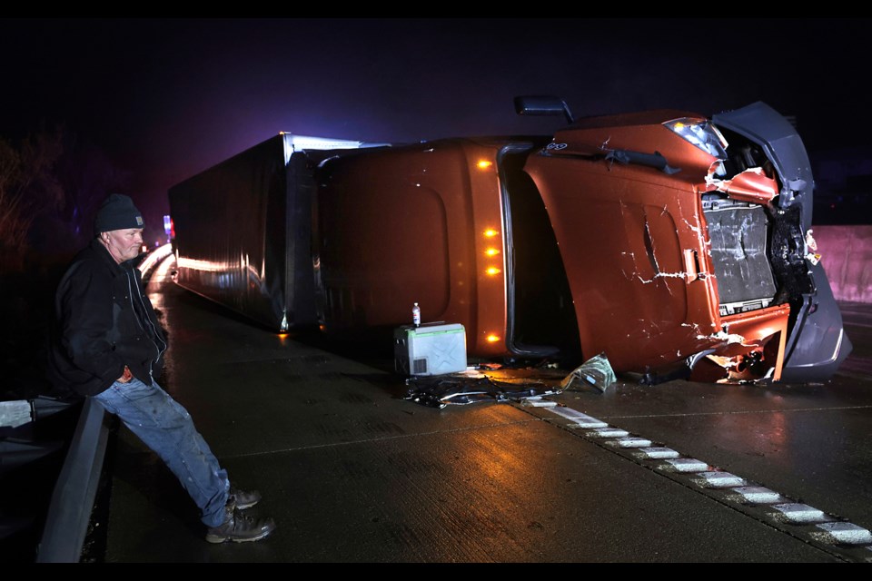 Mark Nelson, of Wis., waits with his tractor-trailer after it overturned during high winds and a possible tornado on Interstate 44 westbound at Villa Ridge, Mo., Friday, March 14, 2025. (Robert Cohen/St. Louis Post-Dispatch via AP)