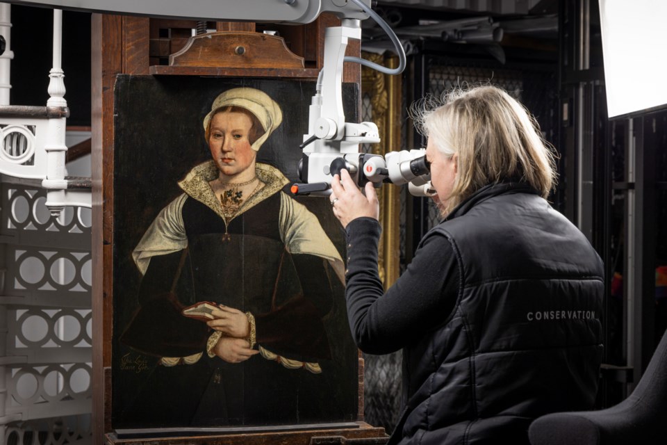 In this photo provided by English Heritage, English Heritage Conservator Rachel Turnbull gives a portrait believed to be of Lady Jane Grey a final examination before it goes on display at Wrest Park in Bedfordshire, England, Feb. 27, 2025. (Christopher Ison, English Heritage via AP)