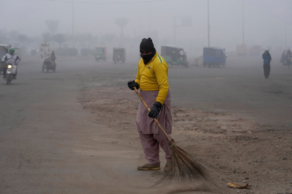 FILE - A sweeper cleans as smog envelops the area and reduces visibility in Lahore, Pakistan, Jan. 11, 2024. (AP Photo/K.M. Chaudary, File)