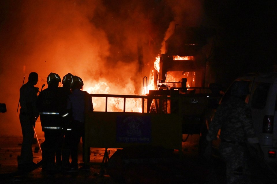 Policemen watch as vehicles are torched during communal clashes sparked by protests demanding removal of the tomb of 17th-century Muslim Mughal ruler Aurangzeb in Nagpur, India, Monday, March 17, 2025. (AP Photo)