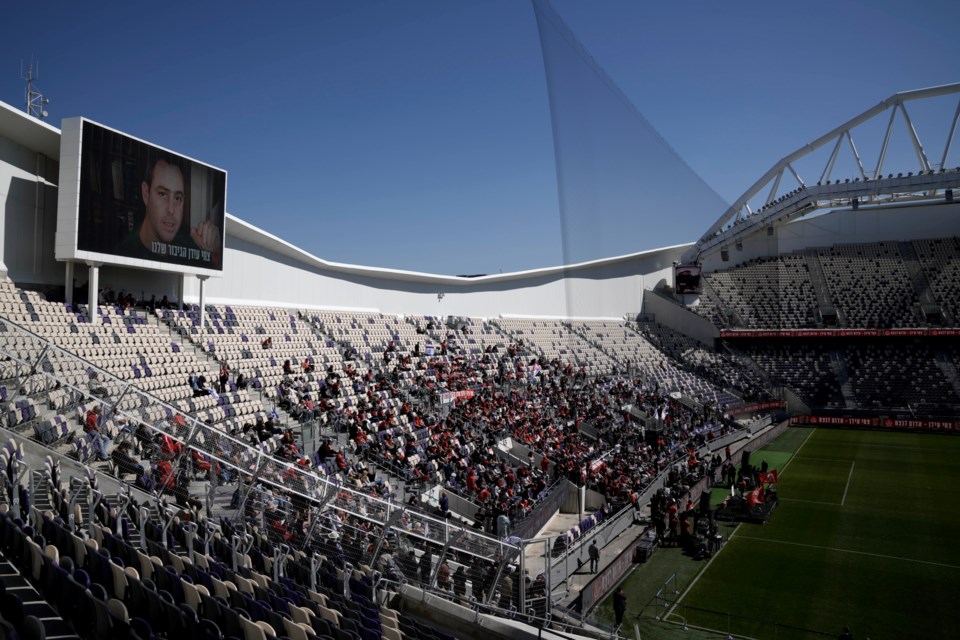 Friends, family and soccer fans attend a public memorial ceremony for slain hostage Tsachi Idan, a fan of Hapoel Tel Aviv F.C., who was killed in Hamas captivity in the Gaza Strip, at Bloomfield Stadium in Tel Aviv, Israel, Friday, Feb. 28, 2025. (AP Photo/Leo Correa)