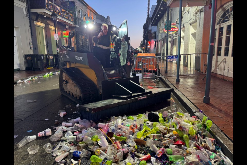 Joe Luscy, an employee with IV Waste, the company tasked with cleaning up the French Quarter after Mardi Gras, coordinates logistics on Ash Wednesday, March 5, 2025, amid a pile of garbage. (AP Photo/Jack Brook)