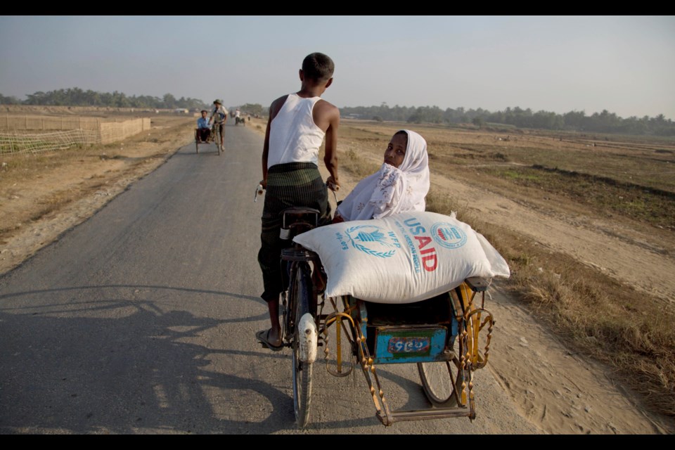 FILE - A Rohingya woman travels with a bag of rice that her family received through World Food Program close to Bawda Pa refugee camp, outskirts Sittwe, Rakhine state, Myanmar, Jan. 15, 2014. (AP Photo/Gemunu Amarasinghe, File)