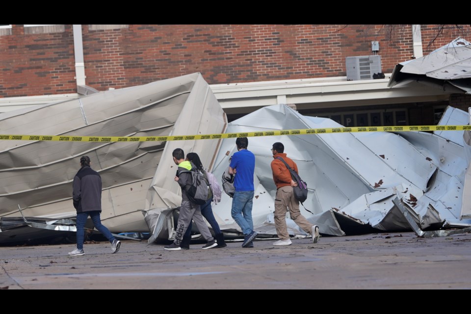 Students arriving for classes walk past damage from the roof that was sheered off by high by winds at Plano West High School Tuesday, March 4, 2025, in Plano, Texas. (AP Photo/LM Otero)