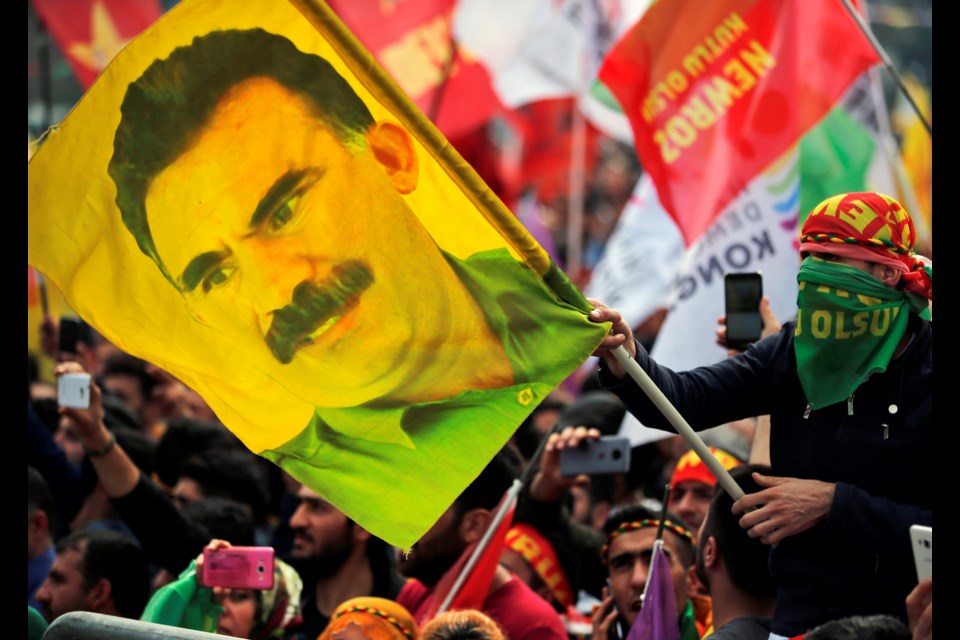 FILE - In this file photo dated Wednesday, March 21, 2018, a youth holds a flag with the image of Abdullah Ocalan, the jailed leader of the rebel Kurdistan Workers' Party, or PKK, in Istanbul, Turkey. (AP Photo/Lefteris Pitarakis, File)