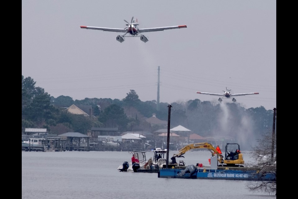 Planes fill bladders with water from the Intracoastal Waterway and empty the water on hot spots in the Carolina Forest wildfire Sunday, March 2, 2025, in Myrtle Beach, S.C. (Janet Morgan/The Post And Courier via AP)