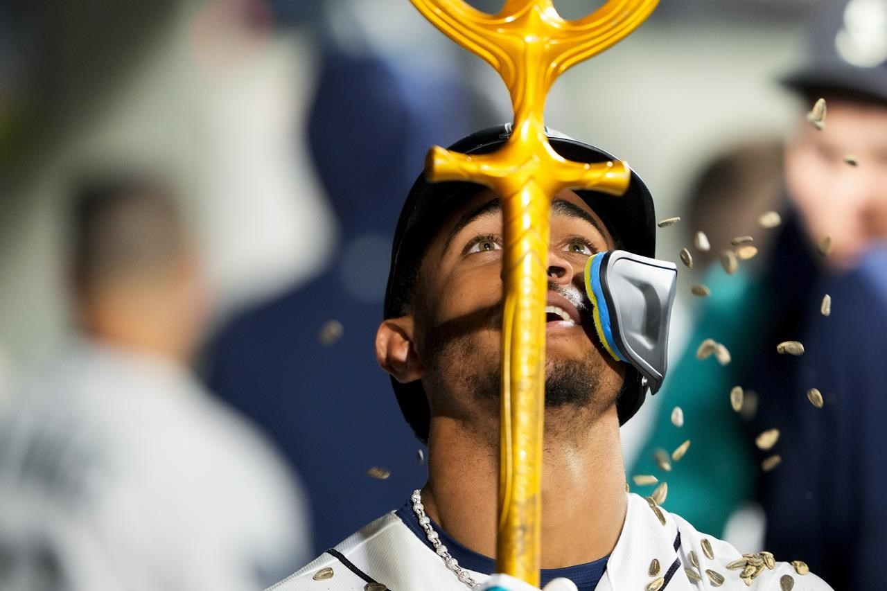 Seattle Mariners' Eugenio Suarez, left, holds a trident in the