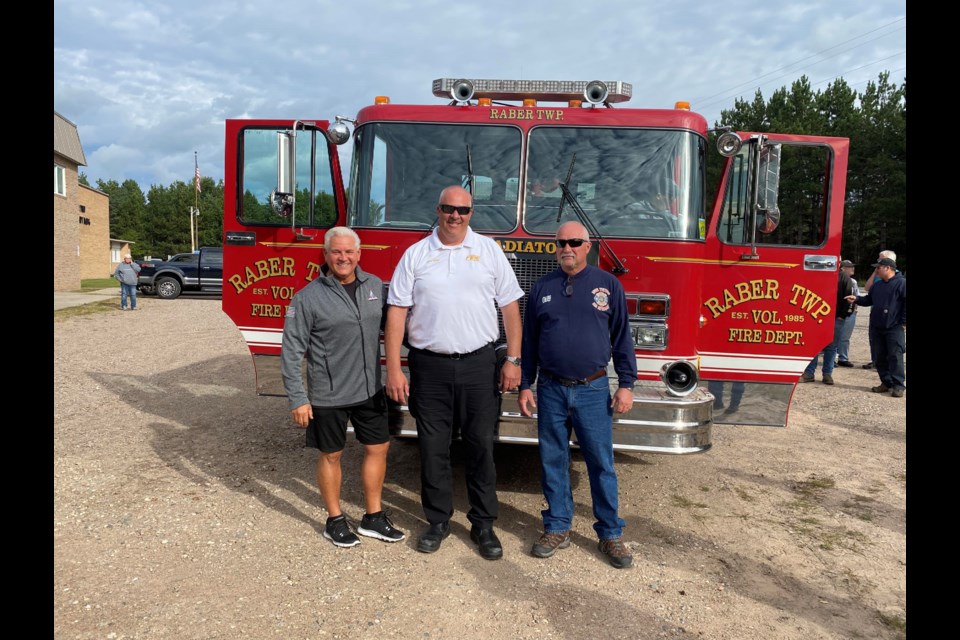 Denny Hughes - from Belfor, Todd Hendy -Fire Chief of Charter Township of Lansing, and Bruce Johnson - Raber VFD Chief stand in front of the donated fire truck.