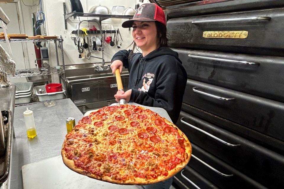 Ali Miller shows off a half pepperoni/onion and half sausage/onion crust pizza.