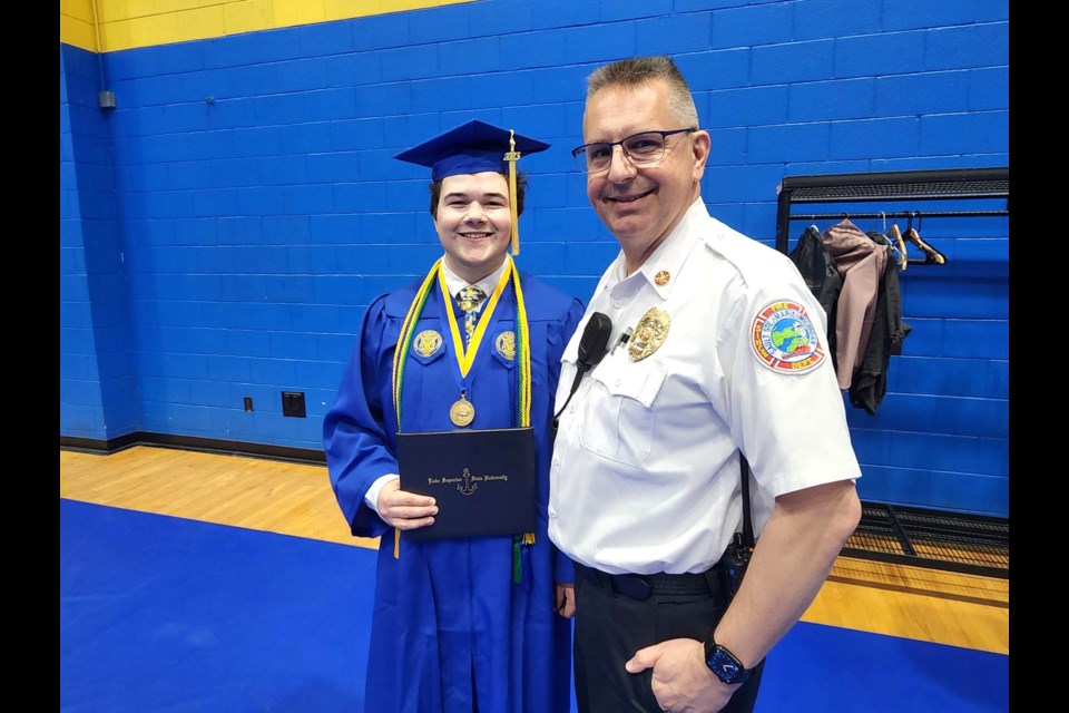 Sault Ste. Marie Fire Department  intern Evan Melville stands next to Chief Ed Miller at Lake Superior State University (LSSU) 2023 Commencement Saturday, May 6