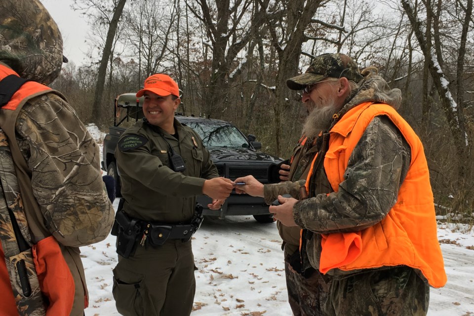 Conservation officer Richard Cardenas talks to a group of hunters in Barry County as he checks their hunting licenses.