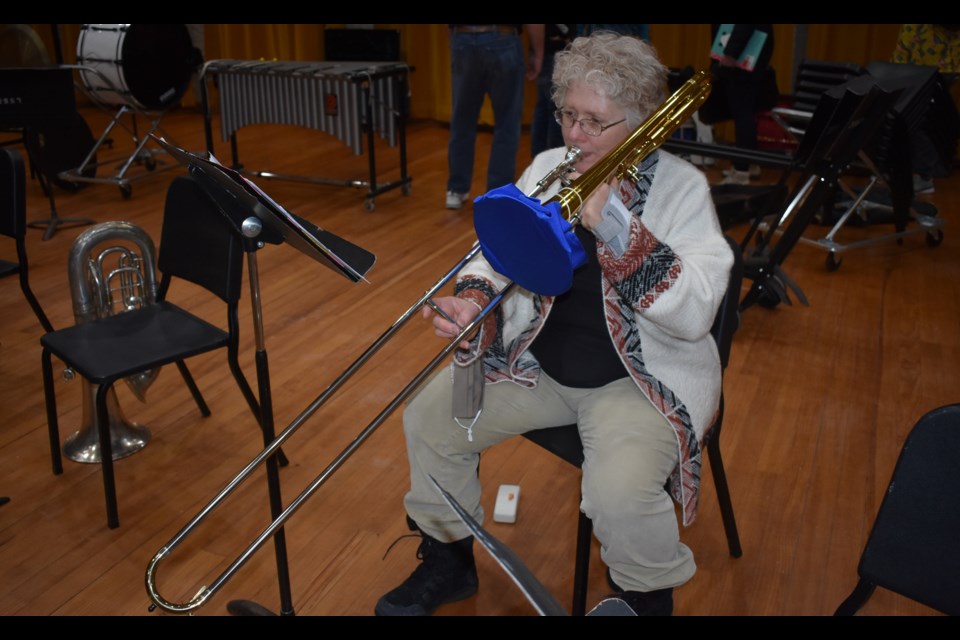 Trombonist Mary Ann Barban warms up with a section from Les Miserables before the start of rehearsal.