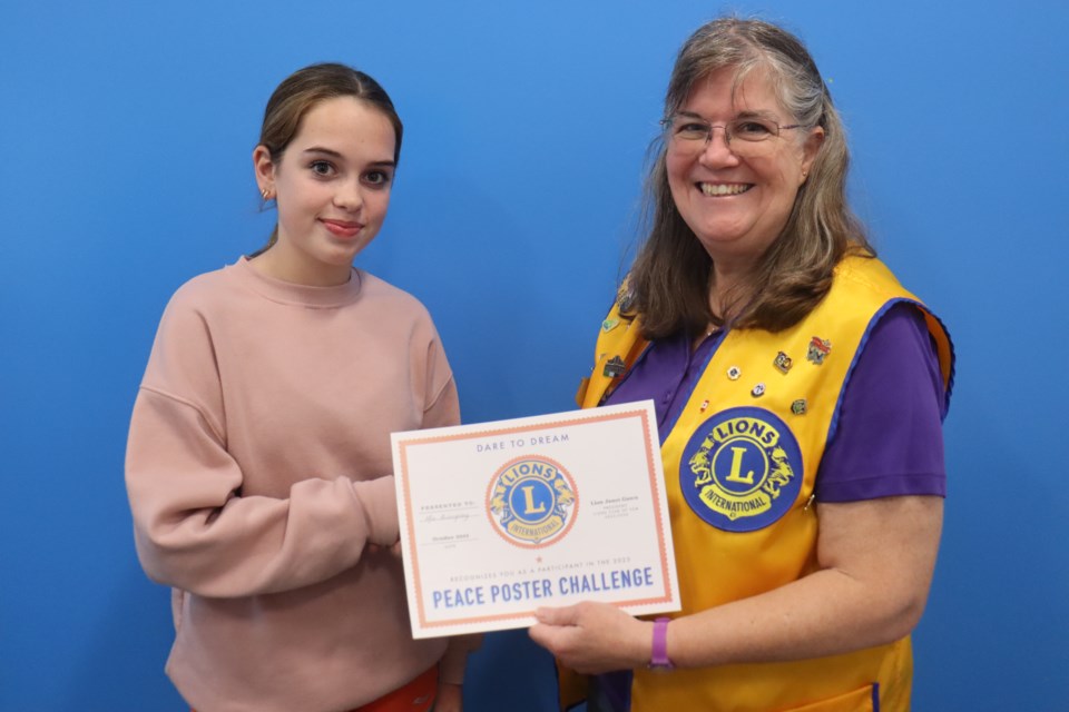 Boreal French Immersion student Mia Billingsley (left) is presented with first place honours by Lions Club member Kim Carter (right) for the 2023 edition of the Peace Poster Contest.