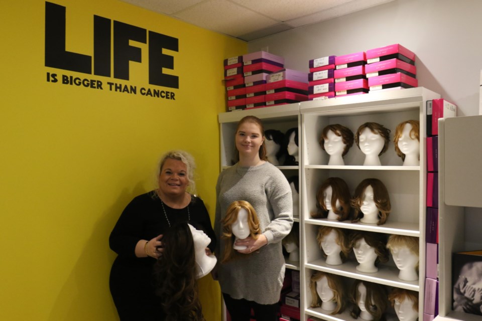 Canadian Cancer Society regional manager Maria Cabral, left, and community fundraising specialist Emily Groulx hold a couple of the wigs available to cancer patients in the organization's new resource room at 143 Great Northern Road during Tuesday's grand re-opening. James Hopkin/SooToday  