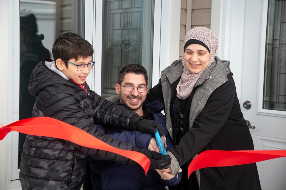 Ahmad and Manal Barakat, with son Zen, cut the ceremonial ribbon to their new Habitat for Humanity home at 23 Blake Street. The family provided a minimum of 500 hours of volunteer time and will pay the mortgage on the home after qualifying for the affordable home ownership program.