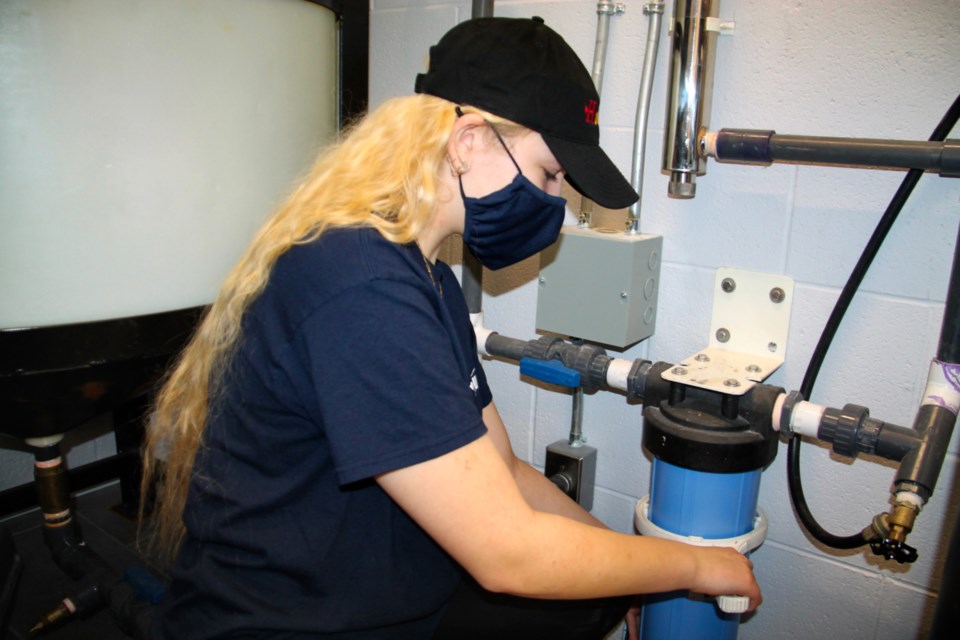 Ashton Brown, a Superior Heights Collegiate Grade 12 student, adjusts a water filter during her work in a skilled trades co-op program with Huckson’s Water Depot, March 7, 2022