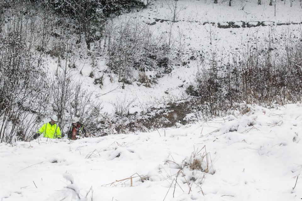 Two men, one with a Government of Ontario logo on his helmet, examine the creek bed Monday near the site of an apparent contaminated wetland near Fort Creek.