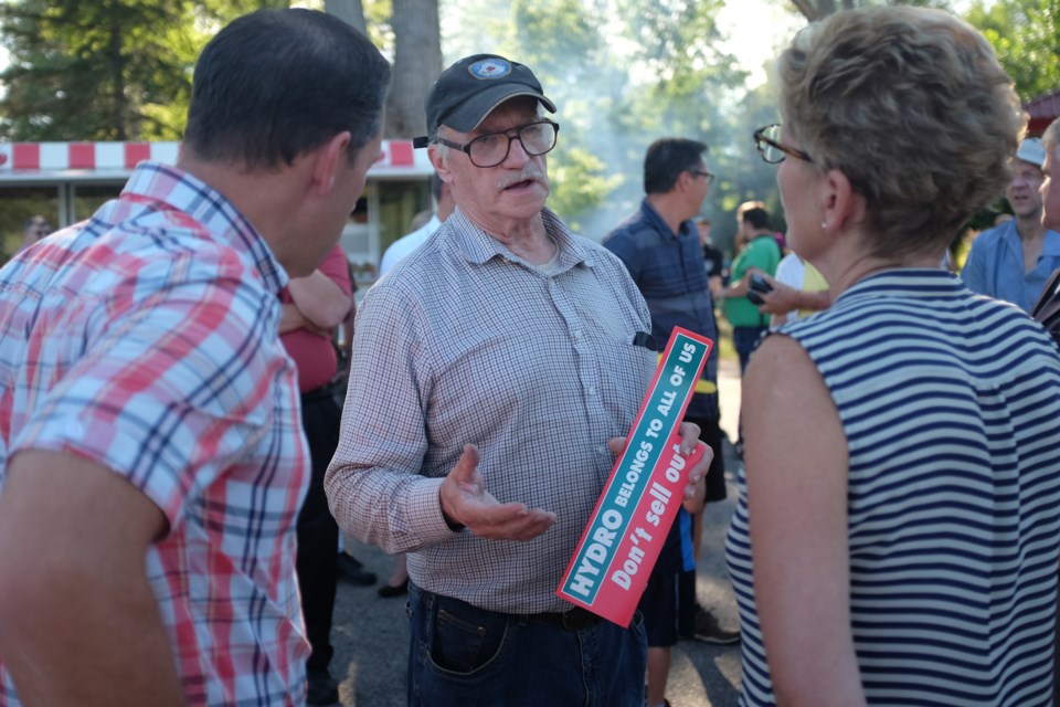 Ontario Premier Kathleen Wynne and Sault MPP David Orazietti held a barbecue and community meet and greet at Bellevue Park Monday evening as was part of their weeklong Northern Ontario tour. Ted Hallin-Williamson was able to get face time with the pair while holding an anti-privatization of Hydro One sticker. Jeff Klassen/SooToday