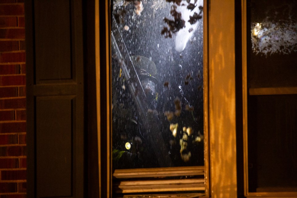 Insulation and other debris falls as a firefighter douses the ceiling on the interior of a house on Dennis Street on Sept. 26, 2024.