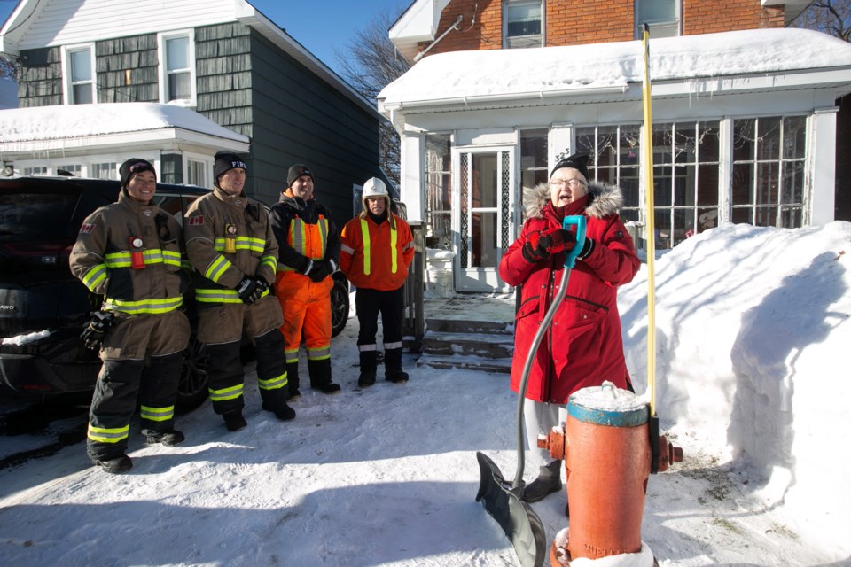 Flanked by firefighters and PUC workers, Karen Grant is this year's first Hydrant Hero to be recognized by PUC and the Sault Ste. Marie Fire Services. For over 70 years she has been clearing the hydrant in front of the central-area home she grew up in.