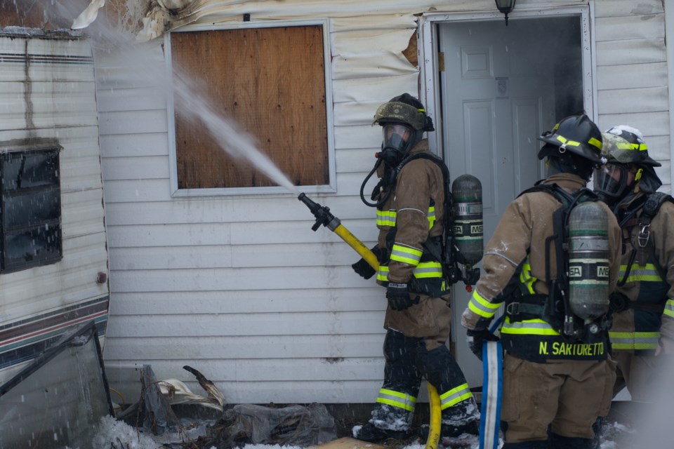 A firefighter applies water to a trailer fire behind a Cathcart Street address on Friday afternoon.