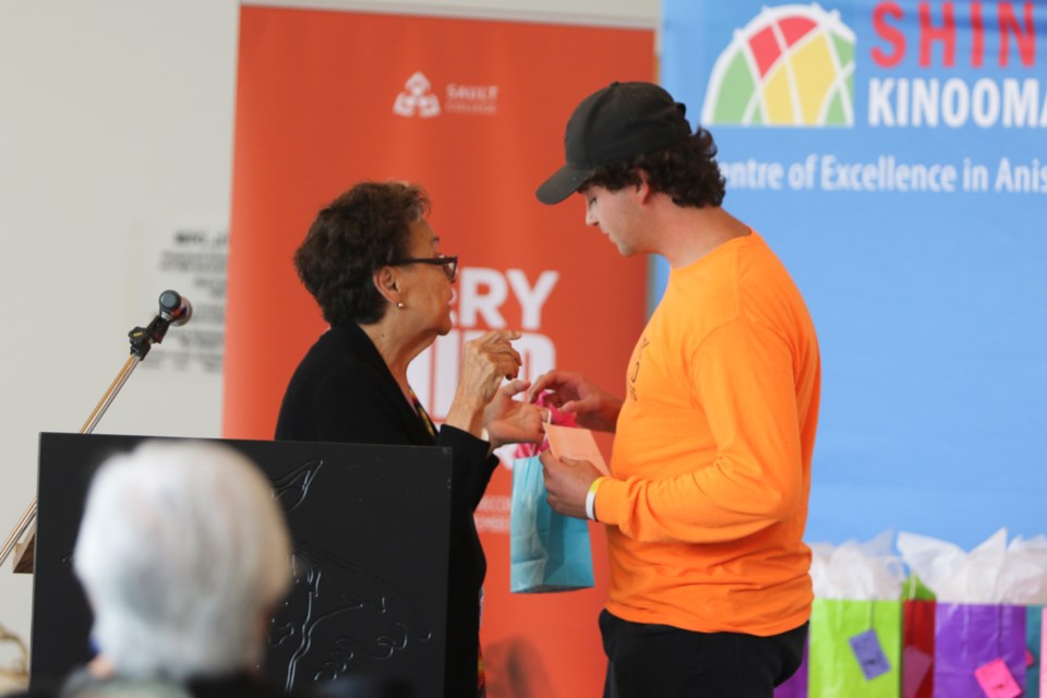 Barbara Nolan presents firekeeper Levi Laundrie, right, with a gift during Nolan's Anishinaabemowin Children's Video Launch event at Shingwauk Kinoomaage Gamig Aug. 24. 