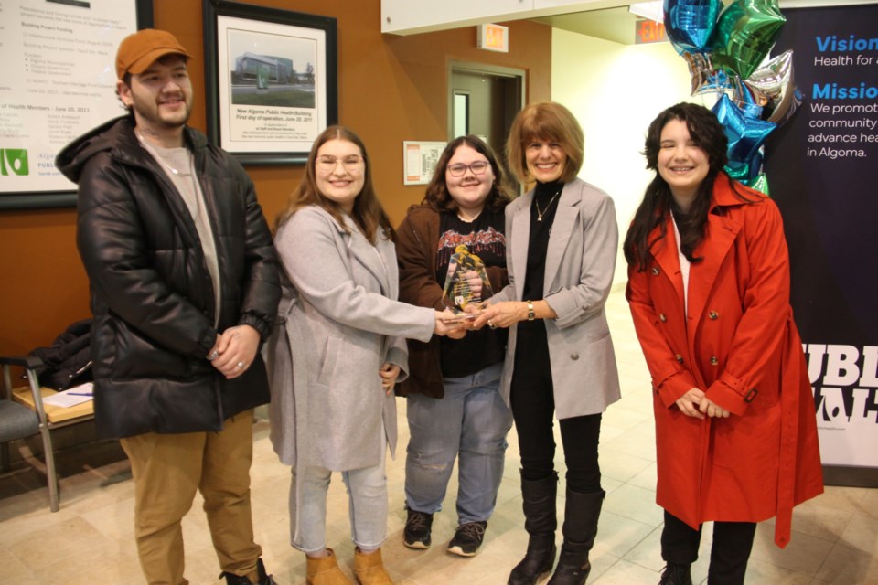 Josh Gareau, Sarah Jordan, Kenda Pennett and Arwen Cooke of New Northern Mentality receive a 2023 Public Health Champion award from Sally Hagman, Algoma Public Health chair, Jan. 24, 2024.