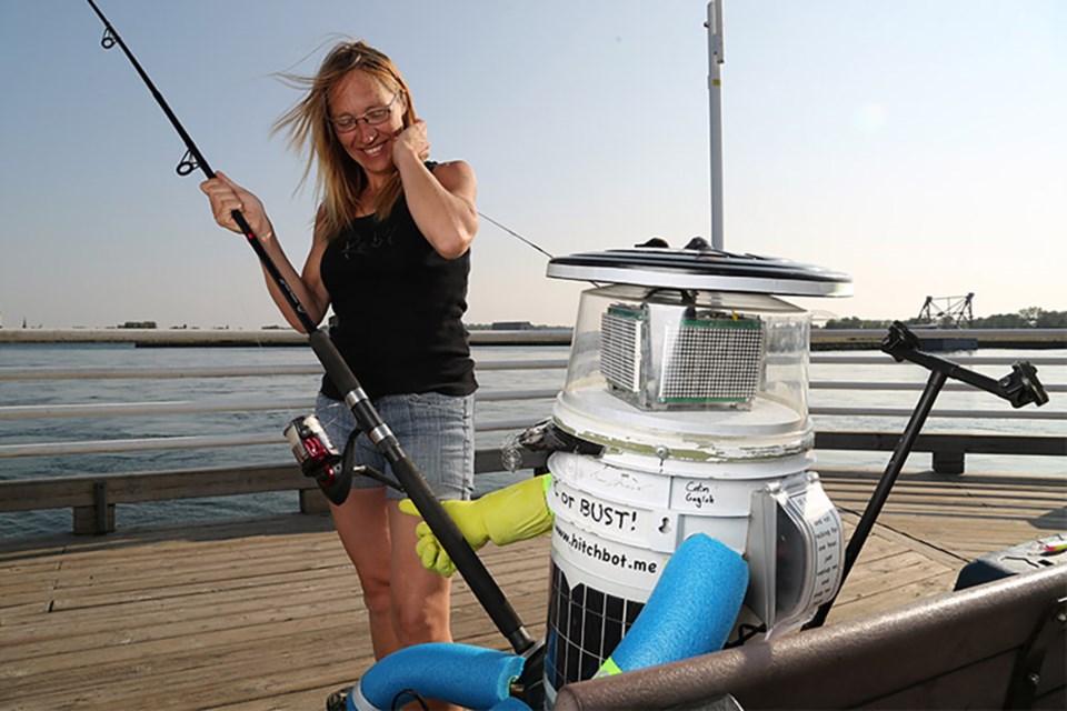 Jen Lemay attempts to hand a fishing rod to hitchBOT Aug. 5, 2014 in Sault Ste. Marie. 