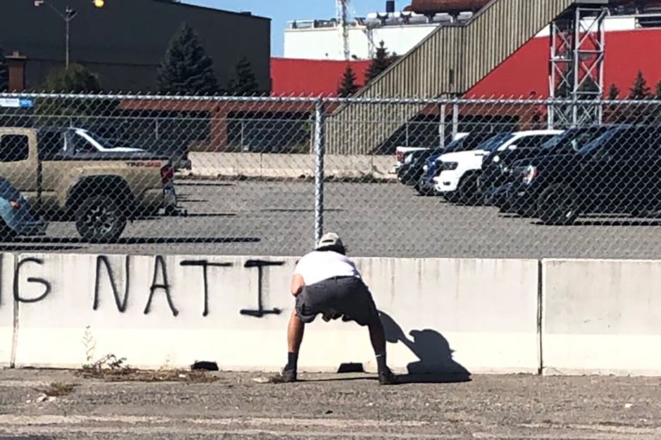 A photo posted anonymously to Facebook appears to show a male spraying anti-Indigenous graffiti on Algoma Steel property. A company spokesperson confirms the black spray paint was removed and that authorities were alerted.