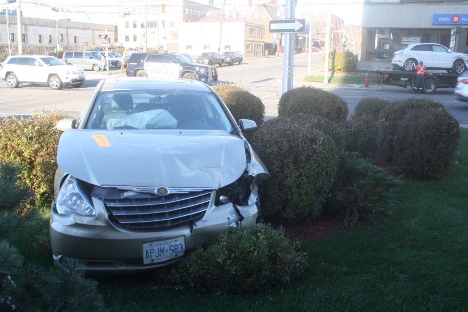 A Chrysler Sebring sits where it came to rest in the corner garden at 421 Bay Street, Station Tower. The  other vehicle involved in the collision can be seen being loaded onto a tow truck. Carol Martin/SooToday