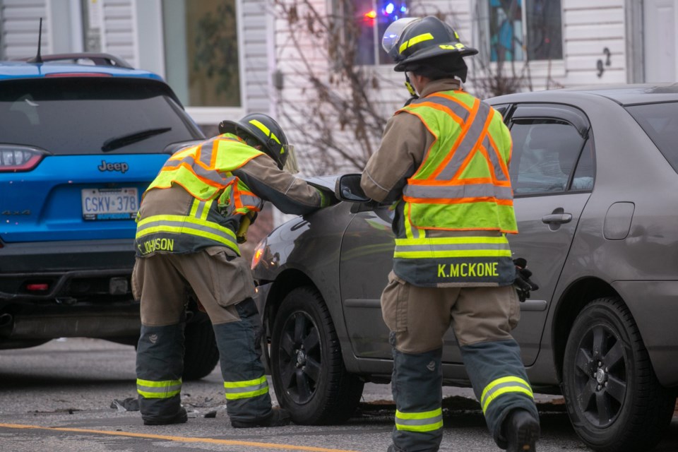 Firefighters attend one of two vehicles involved in a collision Thursday on Wellington Street West.